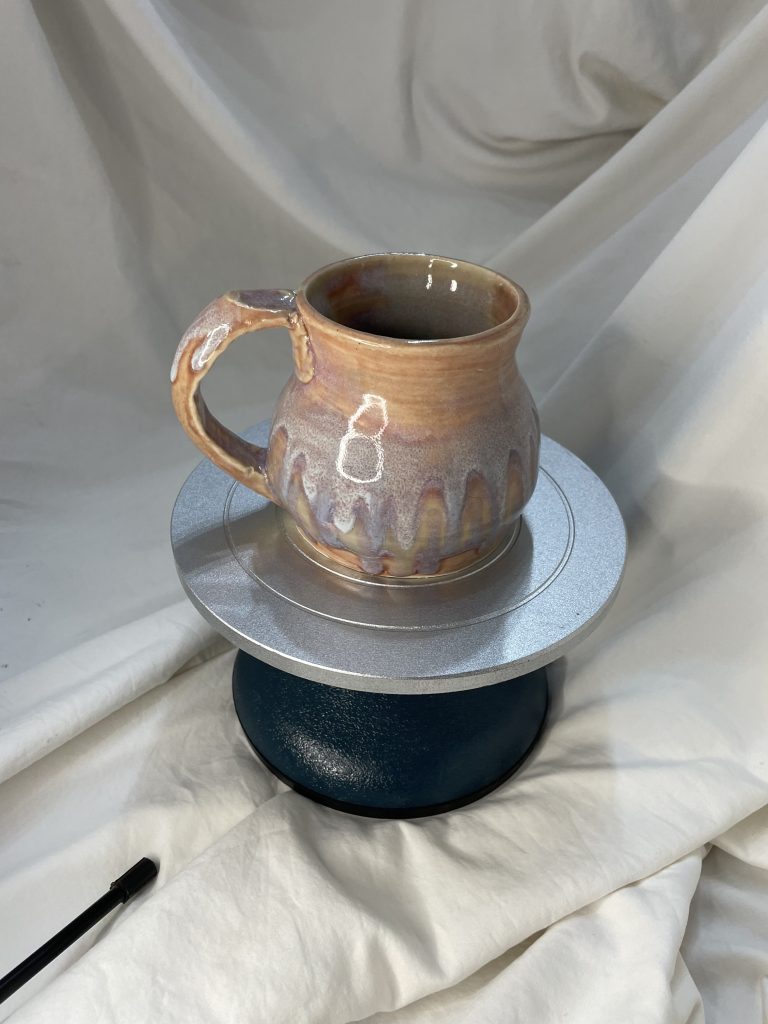 pastel multicolored mug on a cake stand with a white background