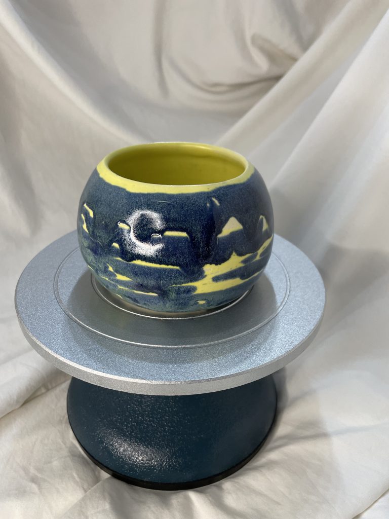 Yellow and blu bowl on a cake stand with a white background