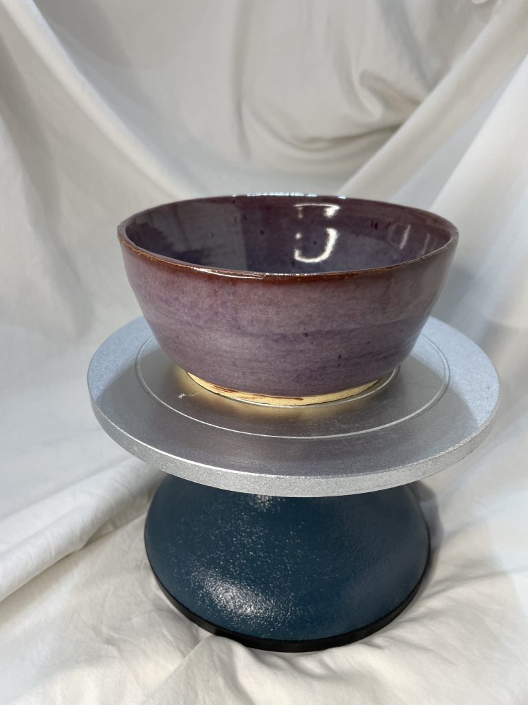 purple bowl on a cake stand with a white background